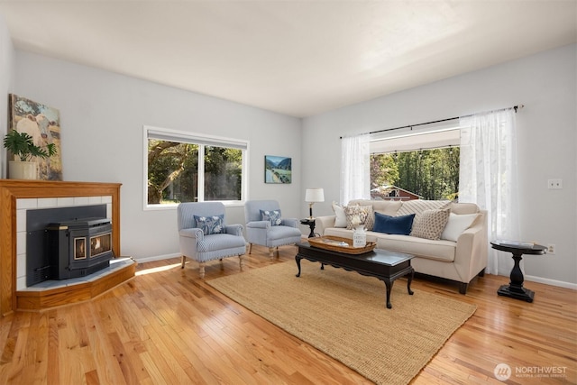 living room with a wood stove, a wealth of natural light, baseboards, and wood-type flooring