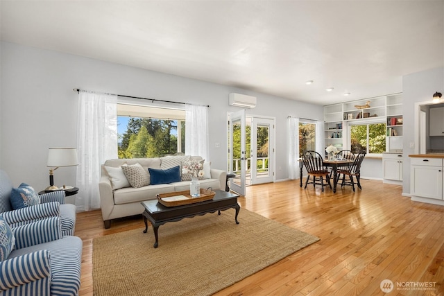 living area with light wood-style floors, french doors, and an AC wall unit