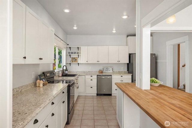 kitchen with a sink, wood counters, open shelves, stainless steel appliances, and white cabinets