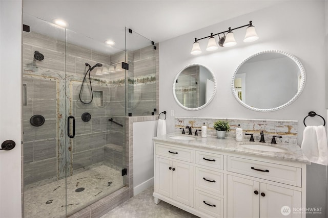 full bath featuring double vanity, a stall shower, and a sink