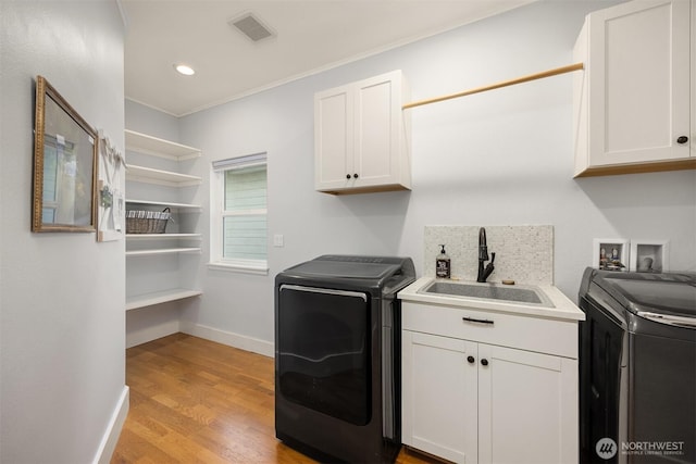 clothes washing area featuring a sink, cabinet space, ornamental molding, visible vents, and light wood-style flooring