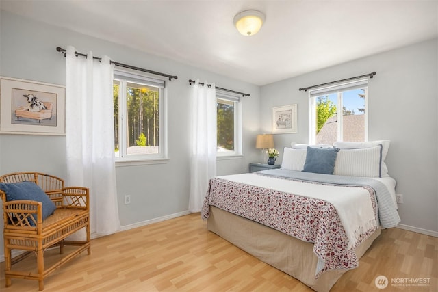 bedroom with baseboards, multiple windows, and wood finished floors