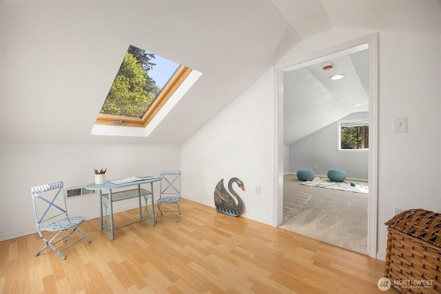 bonus room with baseboards, vaulted ceiling with skylight, and wood finished floors