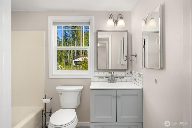 full bathroom featuring toilet, baseboards, vanity, and tasteful backsplash