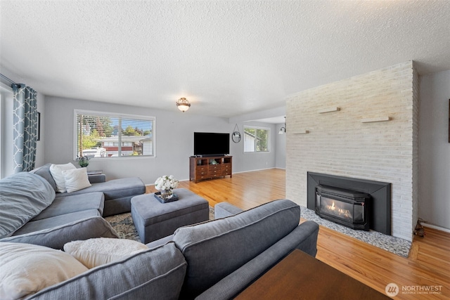 living room with light wood-type flooring, a textured ceiling, and a fireplace