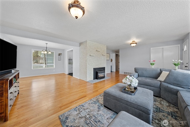 living area featuring wood finished floors, a textured ceiling, a chandelier, and a fireplace