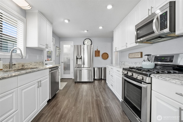 kitchen with appliances with stainless steel finishes, a sink, plenty of natural light, white cabinetry, and recessed lighting