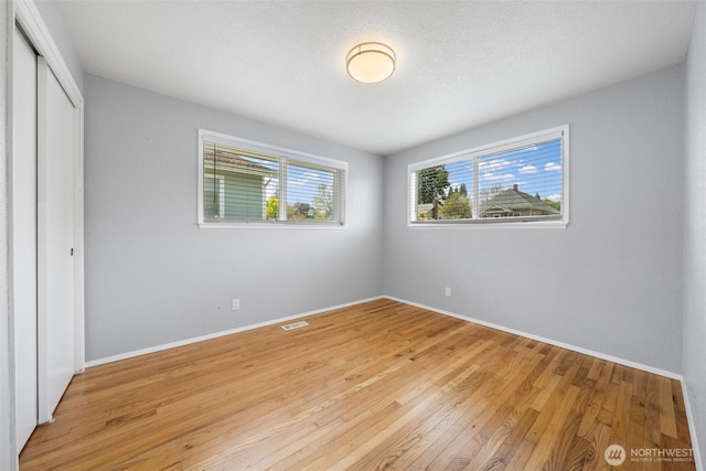 unfurnished bedroom with light wood-style floors, a closet, and baseboards