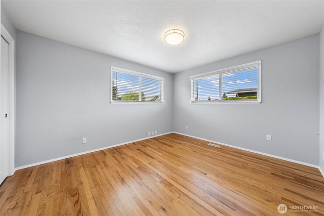 unfurnished bedroom with multiple windows, baseboards, light wood-style floors, and a closet