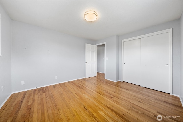 unfurnished bedroom with baseboards, light wood finished floors, and a closet
