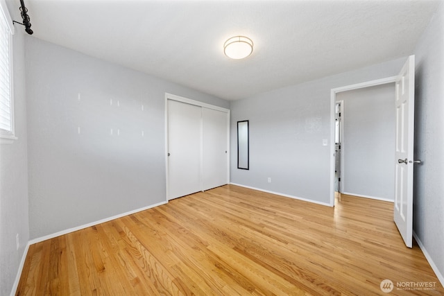 unfurnished bedroom with light wood finished floors, baseboards, and a closet