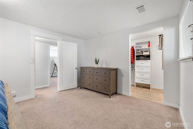carpeted bedroom with a walk in closet, baseboards, and a closet