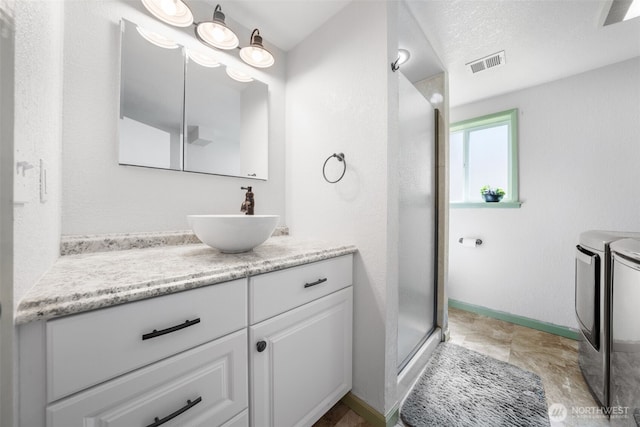 bathroom featuring independent washer and dryer, a stall shower, vanity, and baseboards