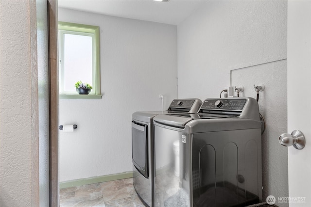 laundry area with washer and dryer, baseboards, and a textured wall