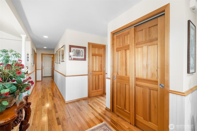 corridor featuring light wood-type flooring and wainscoting