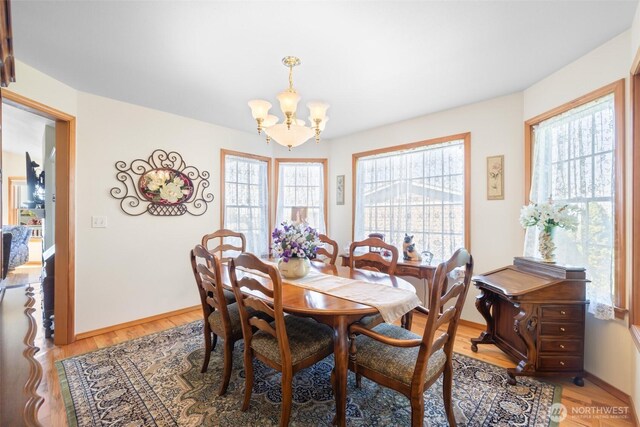 dining room with a chandelier, light wood-type flooring, and baseboards