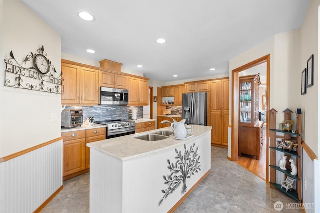 kitchen featuring stainless steel appliances, a sink, decorative backsplash, an island with sink, and recessed lighting