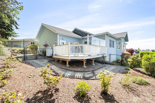 rear view of property featuring a gate, a wooden deck, and fence