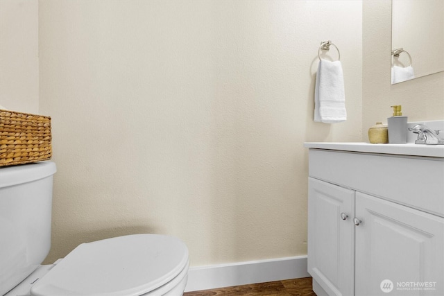 bathroom featuring toilet, vanity, and wood finished floors