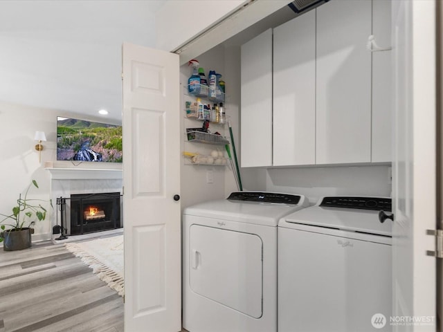 455 Newport Way NW Unit 302, Issaquah, WA 98027 - laundry area with cabinet space, washer and clothes dryer, wood finished floors, and a fireplace