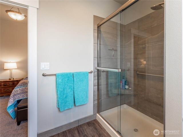 full bath with ensuite bath, a shower stall, and wood finished floors