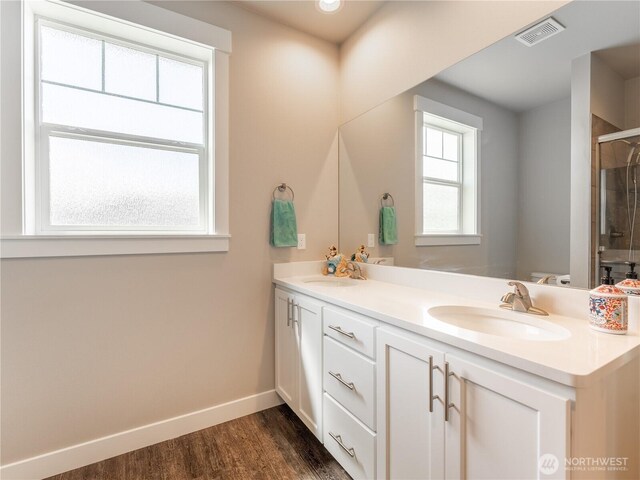 full bath featuring double vanity, wood finished floors, baseboards, and an enclosed shower