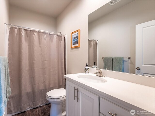 full bathroom with wood finished floors, toilet, vanity, and curtained shower