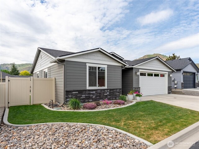 view of front of house with driveway, a garage, stone siding, and roof with shingles
