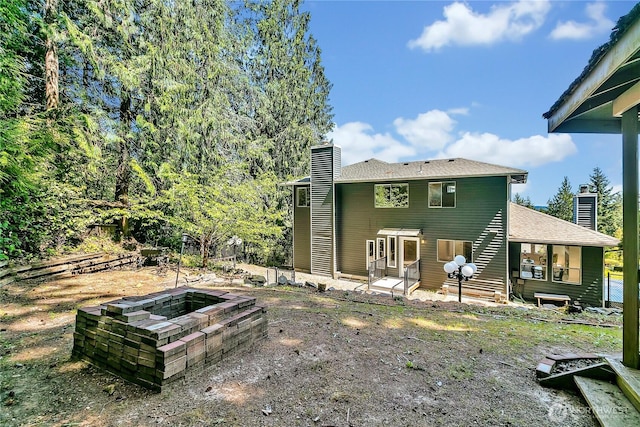 back of house with a fire pit, a patio area, and a chimney