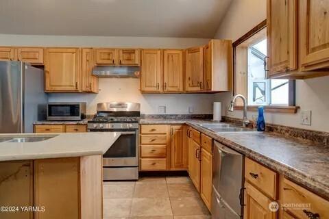 kitchen featuring light tile patterned floors, stainless steel appliances, a sink, and under cabinet range hood