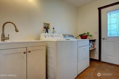 clothes washing area featuring cabinet space, independent washer and dryer, and a sink