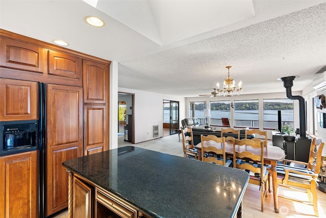 kitchen featuring a chandelier, paneled fridge, open floor plan, a water view, and a textured ceiling