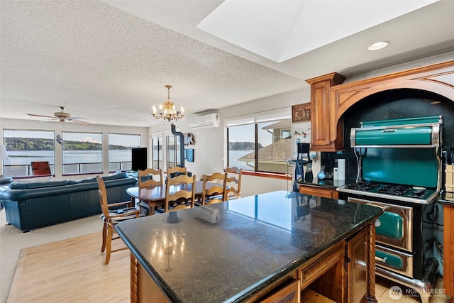 kitchen with a kitchen island, a wall mounted air conditioner, a chandelier, brown cabinetry, and a textured ceiling