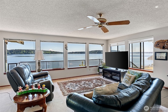 living area featuring a ceiling fan, a textured ceiling, and baseboards