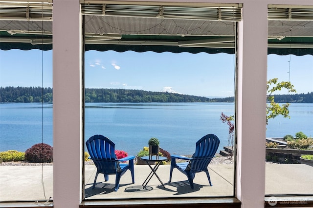 view of patio with a water view and a view of trees