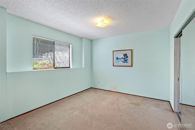 unfurnished bedroom with a closet, carpet, a textured ceiling, and baseboards