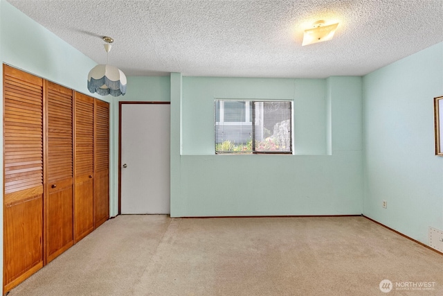 unfurnished bedroom featuring carpet, a textured ceiling, and baseboards