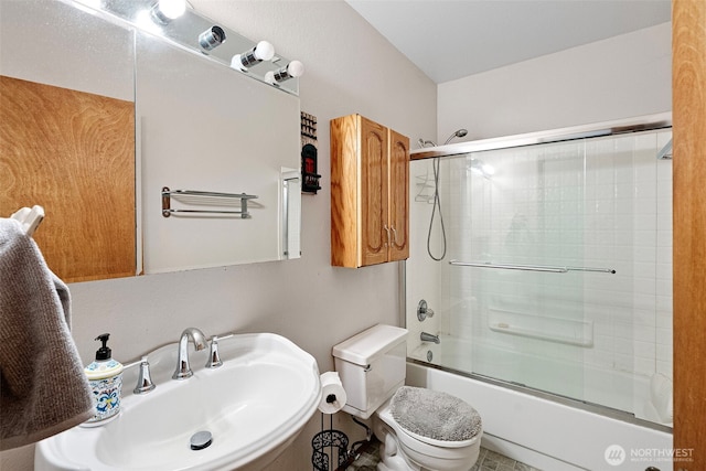 full bathroom with a sink, bath / shower combo with glass door, and toilet