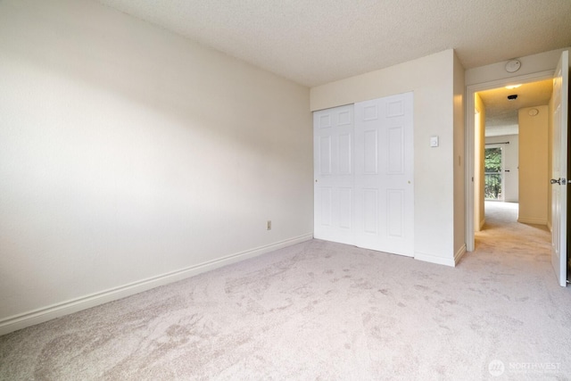 unfurnished bedroom featuring a textured ceiling, carpet floors, baseboards, and a closet