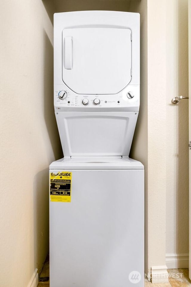 laundry room featuring stacked washing maching and dryer, laundry area, and baseboards
