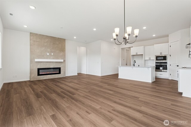 5741 Thornhill Ave SW Unit 326, Port Orchard, WA 98367 - unfurnished living room featuring recessed lighting, a chandelier, wood finished floors, a tiled fireplace, and a sink