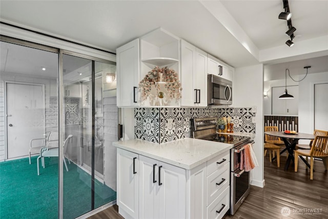 kitchen featuring stainless steel appliances, rail lighting, white cabinets, light stone countertops, and dark wood-style flooring