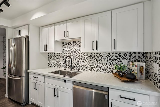 kitchen featuring stainless steel appliances, a sink, white cabinets, light stone counters, and tasteful backsplash