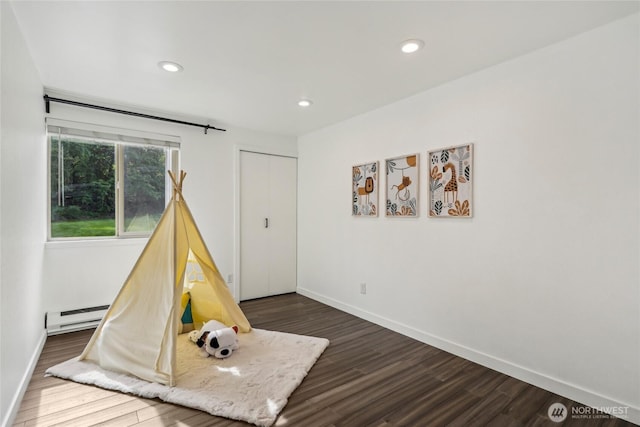 recreation room with a baseboard heating unit, dark wood finished floors, baseboards, and recessed lighting