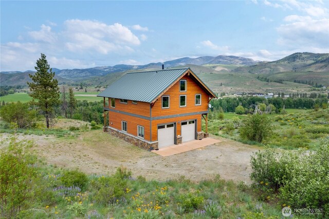 41 Red Tail Ridge Rd, Twisp, WA 98856 - view of property exterior featuring a mountain view, a detached garage, stone siding, a standing seam roof, and metal roof