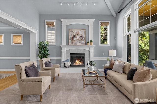 living area with a fireplace, wood finished floors, baseboards, and beamed ceiling