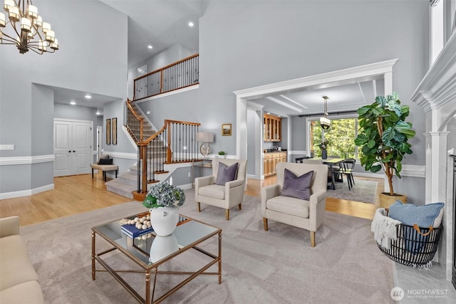 living room with stairway, a chandelier, a high ceiling, light wood-type flooring, and recessed lighting
