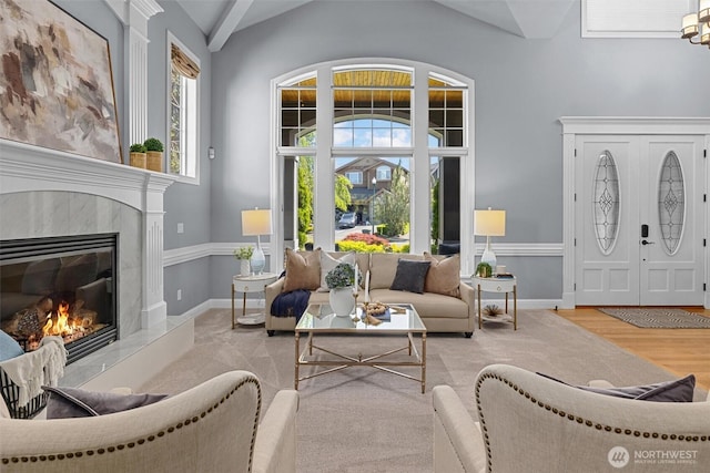 living area with lofted ceiling, a premium fireplace, wood finished floors, and baseboards