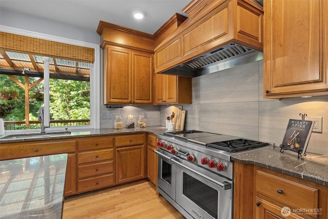 kitchen featuring double oven range, a sink, brown cabinets, and recessed lighting