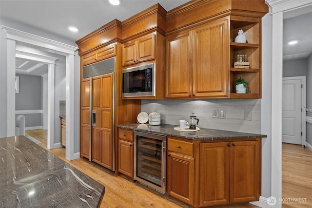 indoor bar featuring beverage cooler, built in appliances, light wood-style flooring, tasteful backsplash, and recessed lighting